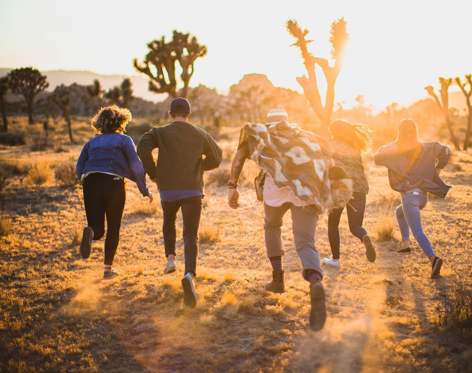 five people running on the field near trees