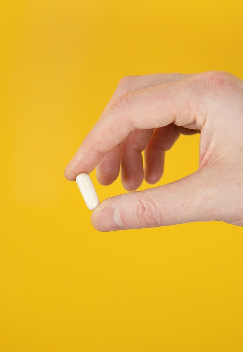 person holding white vitamin pill